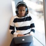 Girl sitting at her laptop, wearing headphones and working.