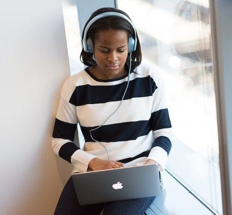 Girl sitting at her laptop, wearing headphones and working.